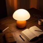 Orange ceramic mushroom lamp lit on wooden desk, warm reading night lamp for home office decor