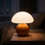 Orange ceramic mushroom lamp lit on wooden bedside table, warm night light for bedroom decor