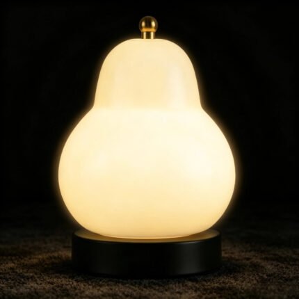 Pear lamp on with warm glow, cream-yellow glass shade and black base